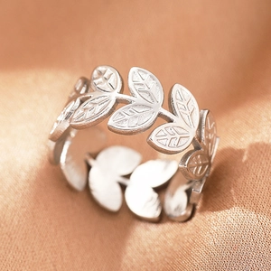 Macro shot of silver laurel leaf ring with fine vein textures on champagne satin fabric