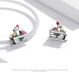Detailed macro view of S925 sterling silver snowman on a sleigh charm with red enamel details