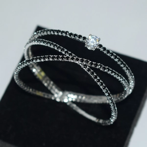 Close-up of a silver crossover bracelet with black stones and a clear round zircon