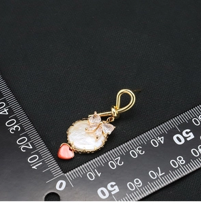 Detail view of gold bow earrings with pearl pendant and red heart measuring 30mm
