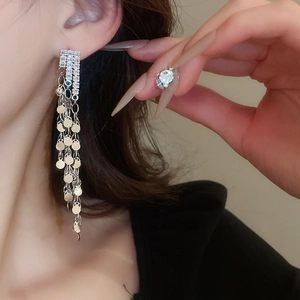 Detail of silver long tassel earrings with sparkling rhinestones and metal sequins on model