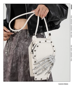 Detail of white PU leather coffin shaped bag featuring a 3D skeleton hand and black rivets