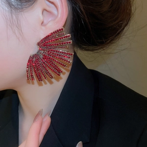 Close-up of a model wearing large red rhinestone fan-shaped stud earrings in a geometric style