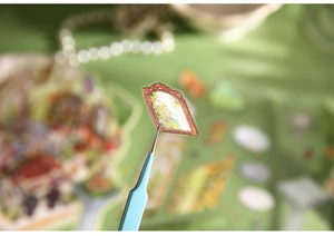 Detail shot of vintage 3D flower stickers being picked up with tweezers for DIY scrapbooking