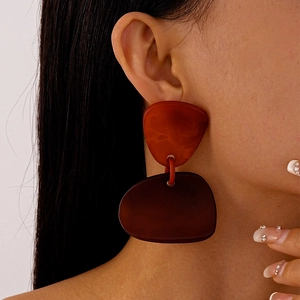 Vue latérale de grandes boucles d'oreilles géométriques en résine marron sur mannequin