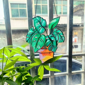 Detail of Monstera plant acrylic window hanging with black outlines and metal chain