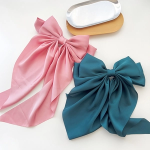 Close-up of pink and dark green satin bow hair clips with long elegant ribbons