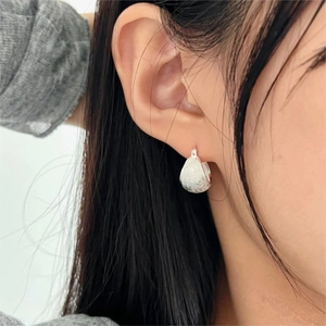 Minimalist 925 sterling silver brushed hoop earrings worn by a model in close-up view