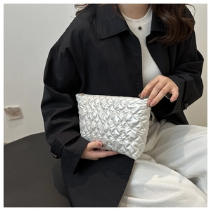 Detail of silver quilted cosmetic bag with metallic finish and soft puffed texture