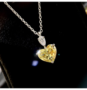 Macro detail of heart-shaped yellow zircon pendant and drop-shaped crystal on silver chain