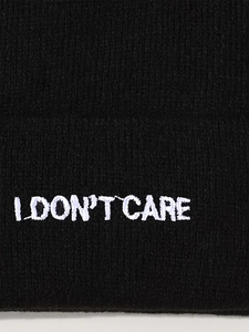 Detail der weißen I DON'T CARE Stickerei auf einer schwarzen Rippstrick-Beanie