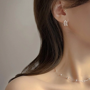 Detailed view of silver twist knot earrings and matching bead chain necklace on model