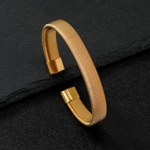 Macro detail of golden wave texture on stainless steel open spring bracelet
