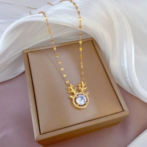 Elegant gold reindeer antler necklace with a sparkling central zircon on a silk background