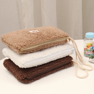 Close-up of three plush cosmetic bags in brown and white with animal patches and zippers