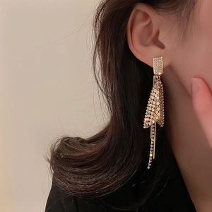 Elegant gold-tone long tassel earrings with sparkling rhinestones on female model