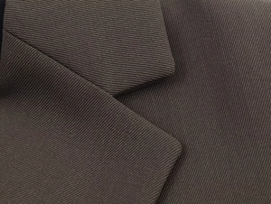 Detailed close-up of dark brown twill weave fabric texture on a formal women's blazer