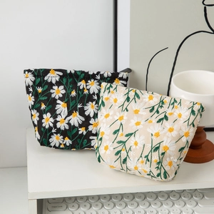 Canvas makeup bags with daisy embroidery in black and cream on a minimalist desk