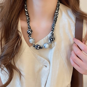 Détail du collier à nœud imprimé léopard avec de grandes perles gris-bleu marbrées