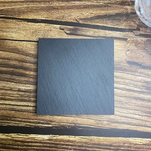 Top-down view of a square black natural slate coaster on a brown wood background