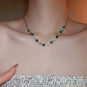 Detail shot of a silver necklace with sparkling green and white round cubic zirconia on a model