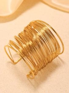 Detail of multi-layer golden wire wrap open cuff bracelet with metallic texture