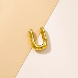 Macro detail of a 3D bubble-style golden letter U pendant with balloon texture
