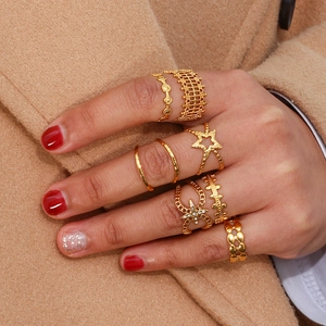 Detail of fashion gold plated woven hollow star rings set worn on a wool coat background
