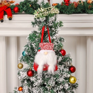 Christmas gnome gift bag hanging on a snowy Christmas tree with festive holiday decorations