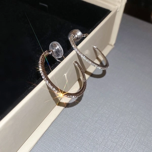 Macro shot of silver C-shaped hoop earrings with sparkling rhinestones on jewelry box