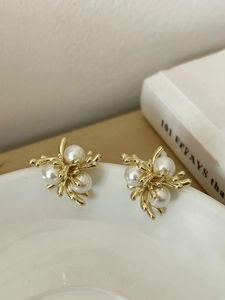 Detailed view of 18k gold plated pearl earrings on a white ceramic dish
