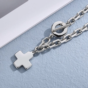 Close-up of silver stainless steel necklace featuring a cross pendant and toggle clasp