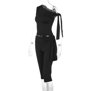 Detail showing the one-shoulder strap design and waist tie on this black two-piece outfit
