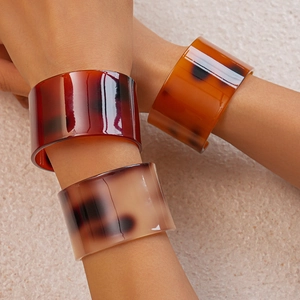 Macro shot of three wide acetate cuff bracelets featuring retro tortoiseshell patterns