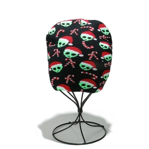 Detail of Christmas knit beanie with green alien and candy cane pattern on a stand