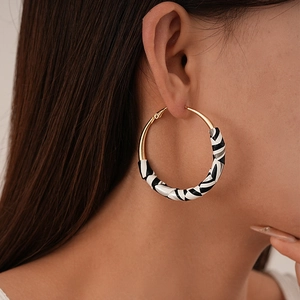 Close-up of stylish large hoop earrings with golden finish and black-white stripe texture