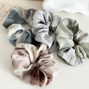 Gros plan de quatre chouchous en tissu plissé tie-dye aux dégradés de couleurs