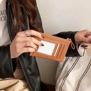 Brown lychee leather card holder with zip pocket and clear ID window held by hand