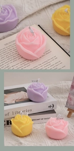 Detailed view of pink rose scented candles placed on an open vintage book for decor