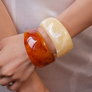 Detail showing marble texture on wide resin geometric bangles in amber and cream colors