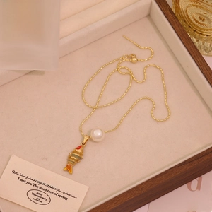 Gros plan d'un pendentif carpe koi avec perle sur une chaîne à billes dorée vintage
