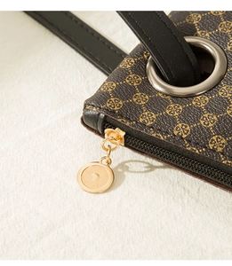Detail of dark brown crocodile texture bag with gold clover pattern and metal zipper