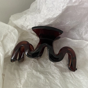 Detail of wave-shaped brown tortoiseshell hair claw clip with glossy acrylic finish
