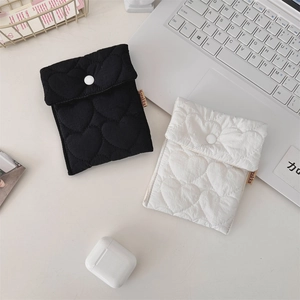 Close-up of black and white cotton quilted storage pouches with heart patterns on a desk