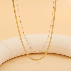Detail einer goldenen Doppelkette mit Schlangenkette und edlen weißen Perlen