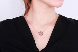 Detail of rose gold snowflake pendant necklace worn by a model for a stylish look