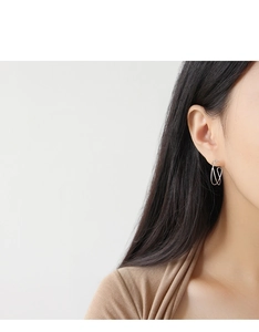 Close-up of minimalist interlocking wave earrings in S925 sterling silver on model