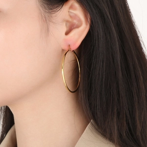 Primo piano di una donna che indossa grandi orecchini a cerchio cavi placcati oro 18K