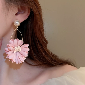 Detail view of large pink fabric flower earrings with white pearl studs and gold metal rings