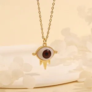 Macro detail of 18K gold evil eye necklace with brown eyeball and spiked lash charms